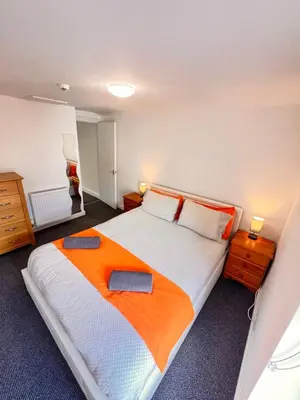 a bedroom with a large bed with an orange blanket at The Brooklyn loft apartment in Blackpool
