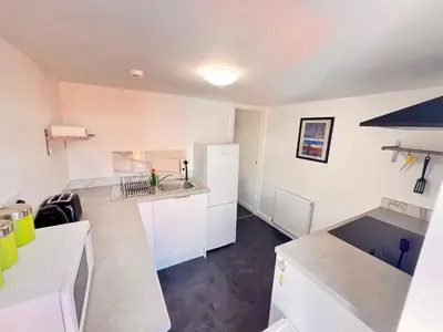 a kitchen with white counters and a white refrigerator at The Brooklyn loft apartment in Blackpool