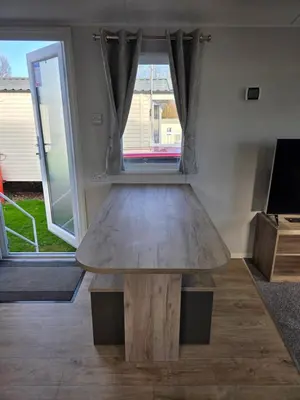 a wooden table in a living room with a window at 8 Berth Caravan Haven Marton Mere in Blackpool