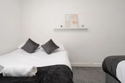 a white bed with black pillows in a bedroom at Huge Apartment - 8 Beds - Free Parking - Long Stays! in Liverpool