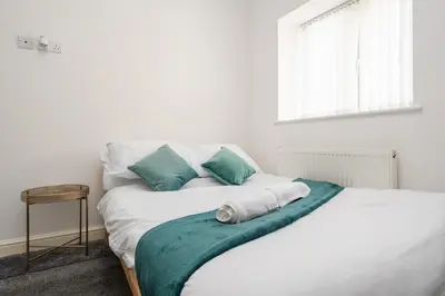 a white bed with green and white pillows and a window at Huge Apartment - 8 Beds - Free Parking - Long Stays! in Liverpool