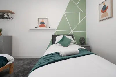 a bedroom with a white bed with green accents at Huge Apartment - 8 Beds - Free Parking - Long Stays! in Liverpool