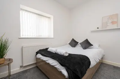 a white bedroom with a bed with white sheets and pillows at Huge Apartment - 8 Beds - Free Parking - Long Stays! in Liverpool
