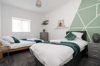 two beds in a room with white and green at Huge Apartment - 8 Beds - Free Parking - Long Stays! in Liverpool