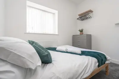 a white bedroom with a bed and a window at Huge Apartment - 8 Beds - Free Parking - Long Stays! in Liverpool