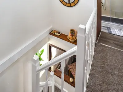 a stairway with a white rail with a wooden table at Seagull Cottage in Heysham
