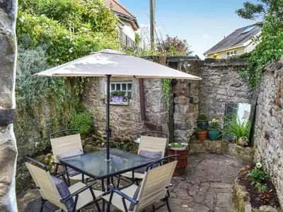 a table and chairs with an umbrella on a patio at Seagull Cottage in Heysham