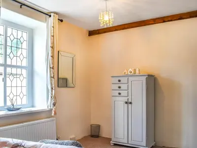 a bedroom with a white cabinet and a window at Seagull Cottage in Heysham
