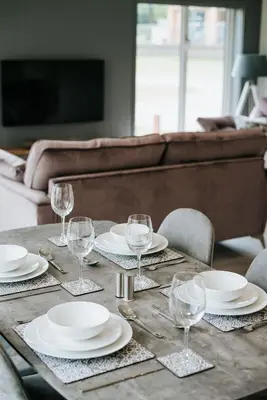 a wooden table with plates and wine glasses on it at Nash - Bowland Retreat Lodges Clitheroe, Ribble Valley, Lancashire in Clitheroe