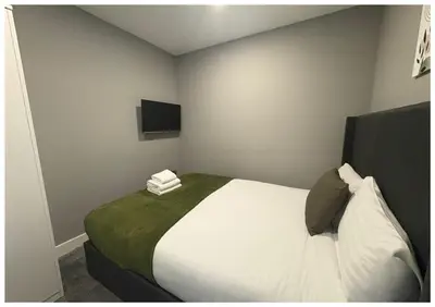 a bedroom with a large white bed with a green blanket at Monarchs Quay Arena Apartments by Happy Days in Liverpool