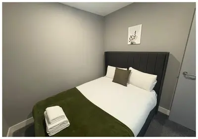 a bedroom with a bed with white sheets and green blanket at Monarchs Quay Arena Apartments by Happy Days in Liverpool
