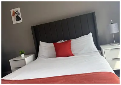a bedroom with a large bed with a red pillow at Monarchs Quay Arena Apartments by Happy Days in Liverpool