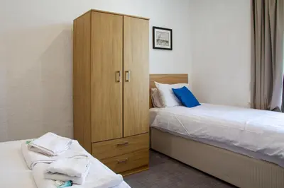 a bedroom with two beds and a wooden cabinet at The Highlands, Bispham in Blackpool