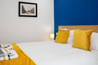 a bedroom with a white bed with yellow pillows at The Highlands, Bispham in Blackpool