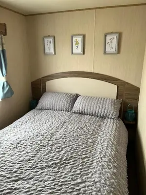 a bed in a bedroom with three pictures on the wall at A fully equiped caravan Marton mere haven in Blackpool