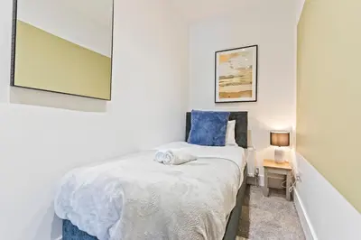 a small bedroom with a bed and a table at Stylish House - Sleeps 7 - Free Parking, Fast WiFi and Smart TV - Contractors, Groups and Long Stays Welcome by Yoko Property in Wigan