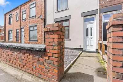 a brick wall in front of a building at Stylish House - Sleeps 7 - Free Parking, Fast WiFi and Smart TV - Contractors, Groups and Long Stays Welcome by Yoko Property in Wigan