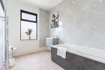 a bathroom with a bath tub and a window at Stylish House - Sleeps 7 - Free Parking, Fast WiFi and Smart TV - Contractors, Groups and Long Stays Welcome by Yoko Property in Wigan