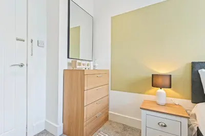 a bedroom with a dresser and a mirror at Stylish House - Sleeps 7 - Free Parking, Fast WiFi and Smart TV - Contractors, Groups and Long Stays Welcome by Yoko Property in Wigan