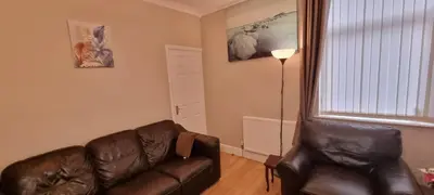 a living room with a leather couch and a lamp at A nice home in Liverpool in Liverpool
