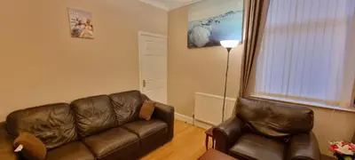 a living room with a leather couch and a lamp at A nice home in Liverpool in Liverpool