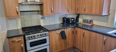 a kitchen with wooden cabinets and a stove top oven at A nice home in Liverpool in Liverpool