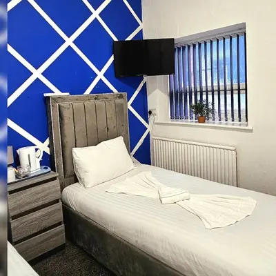 a bedroom with a bed with a blue wall at Sapphire hotel blackpool promenade in Blackpool
