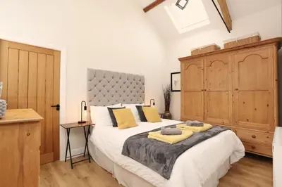 a bedroom with a large bed and a wooden cabinet at Stunning Coach House with two bedrooms and parking in Hambleton