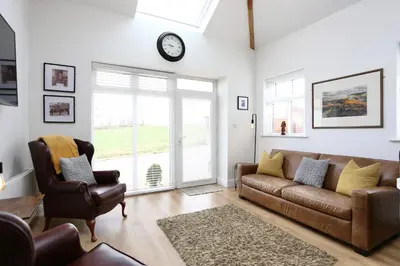 a living room with a couch and a chair and a clock at Stunning Coach House with two bedrooms and parking in Hambleton