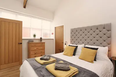 a bedroom with a large bed with yellow pillows at Stunning Coach House with two bedrooms and parking in Hambleton