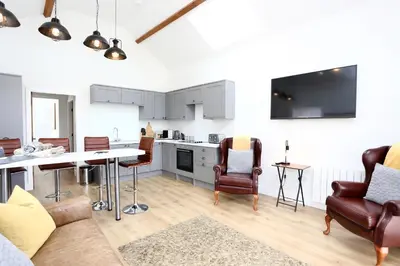 a kitchen and living room with a table and chairs at Stunning Coach House with two bedrooms and parking in Hambleton