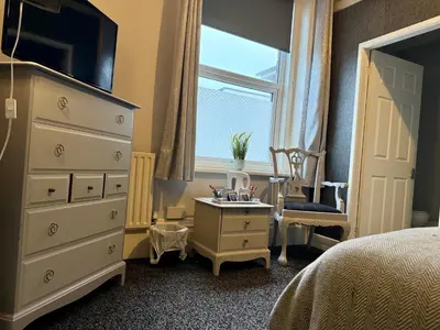 a bedroom with a dresser and a window and a chair at St Andrews house Hotel in Preston