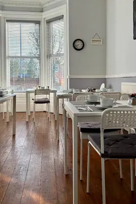 a dining room with tables and chairs and a clock on the wall at St Andrews house Hotel in Preston