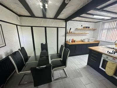 a room with chairs and a table and a kitchen at Modern Pink Cottage in Blackpool in Blackpool