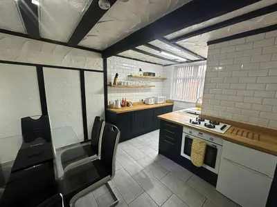 a kitchen with black cabinets and a table and chairs at Modern Pink Cottage in Blackpool in Blackpool