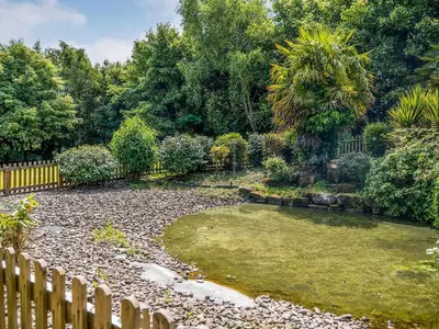 a garden with a fence and a pond at The Farmhouse At Ream Hills in Weeton
