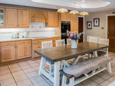a kitchen with a wooden table with a vase of flowers at The Farmhouse At Ream Hills in Weeton