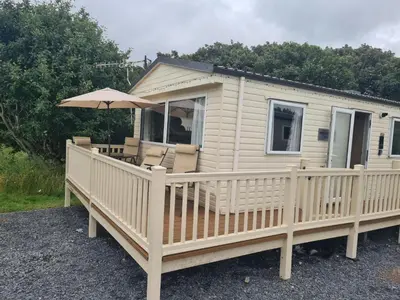 a mobile home with a deck and an umbrella at The Mayflower in Millom