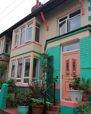 a colorful house with a red door and some plants at Aqua View, New Brighton Beach- 2 Bedroom with BALCONY & VIEW in New Brighton