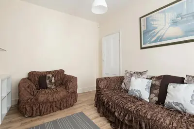 a living room with a couch and a chair at Comfy Home King Size Bed close to Asda & Sefton Park, Very Fast WIFI! in Liverpool
