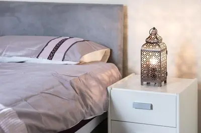 a bed with a night stand with a lantern on it at Comfy Home King Size Bed close to Asda & Sefton Park, Very Fast WIFI! in Liverpool