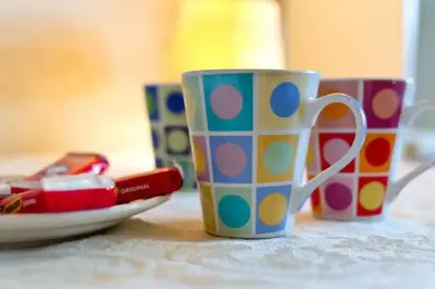 three colorful cups sitting on a table with a plate at Comfy Home King Size Bed close to Asda & Sefton Park, Very Fast WIFI! in Liverpool
