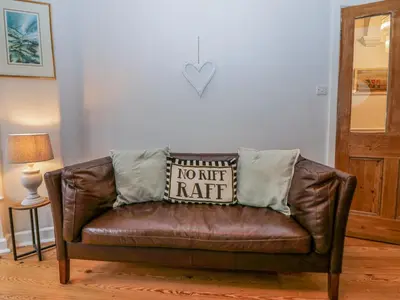 a brown leather couch with a no net rat pillow on it at Willow Cottage in Carnforth