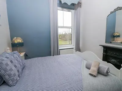 a blue bedroom with a bed and a window at Willow Cottage in Carnforth