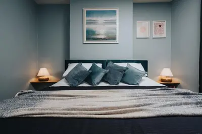 a bedroom with a large bed with blue walls at The Tides, 3 bed house Morecambe in Morecambe