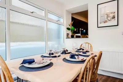 a dining room with a table with glasses and chairs at The Tides, 3 bed house Morecambe in Morecambe