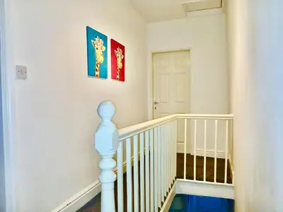 a room with a staircase with a crib and paintings on the wall at Liverpool 4 Bed Home Sleeps 18 Free Parking in Liverpool