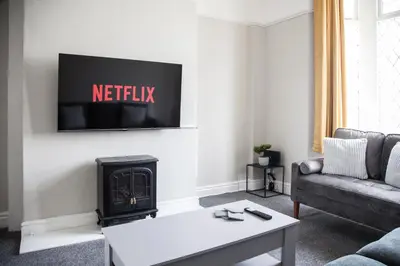 a living room with a fireplace and a tv on the wall at Spacious House 10min to Liverpool Centre in Wallasey