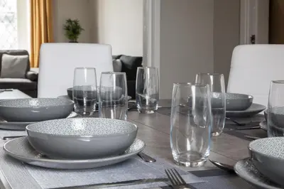 a table with plates and bowls and glasses on it at Spacious House 10min to Liverpool Centre in Wallasey