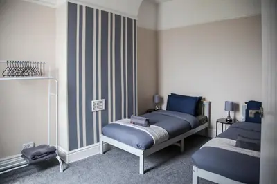 a bedroom with two beds with blue sheets at Spacious House 10min to Liverpool Centre in Wallasey